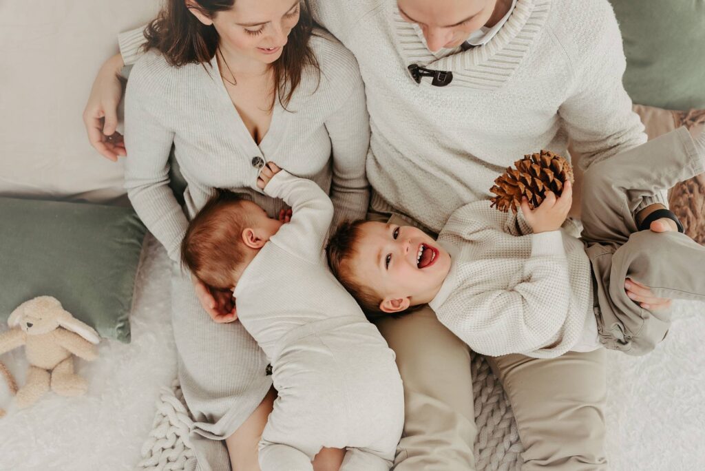 Eltern kuscheln mit zwei kleinen Kindern auf einer Decke, Familienfotos Wien