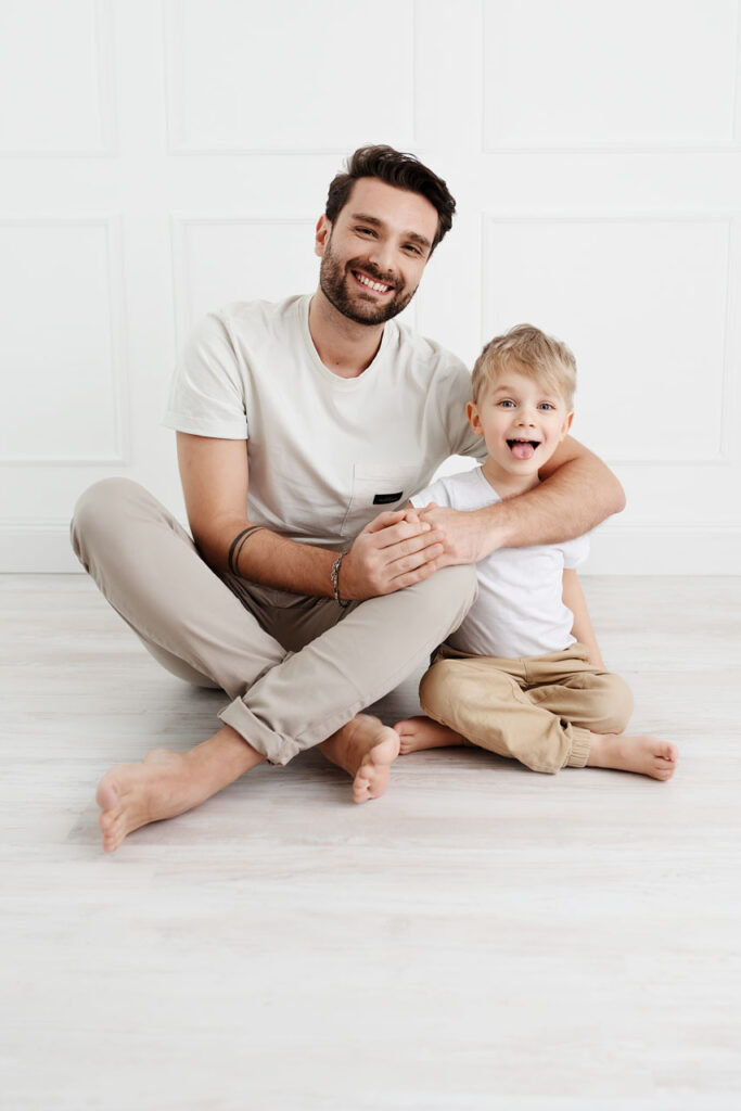 Vater und kleiner Sohn lachen gemeinsam beim Familienfotoshooting