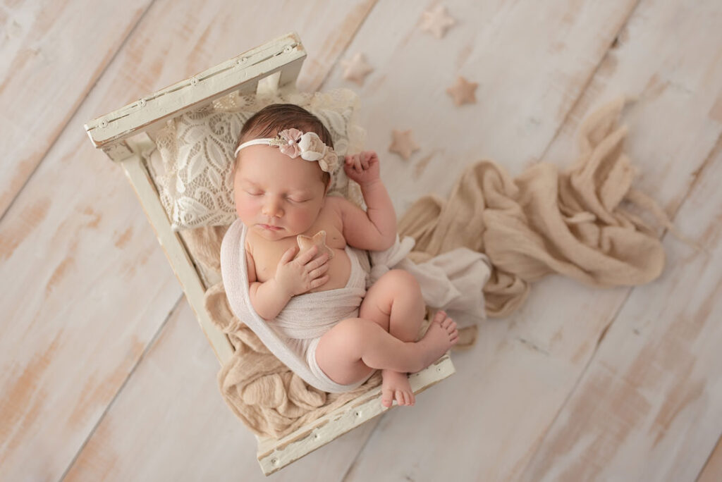Sechs Tage altes Baby schläft in einem kleinen Holzbett, Neugeborenenfotos Wien
