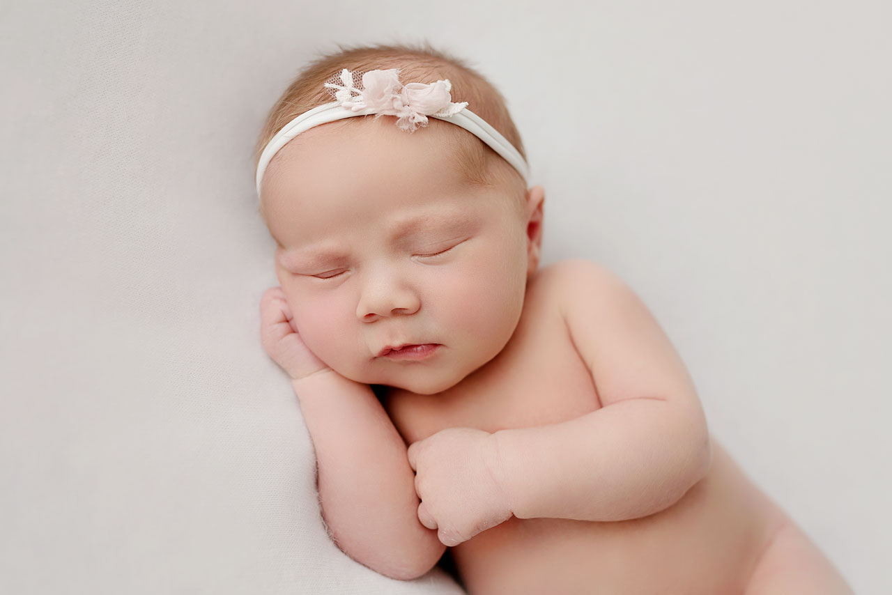 Schlafendes Neugeborenes mit Blumenhaarband, Babyfotografin Wien